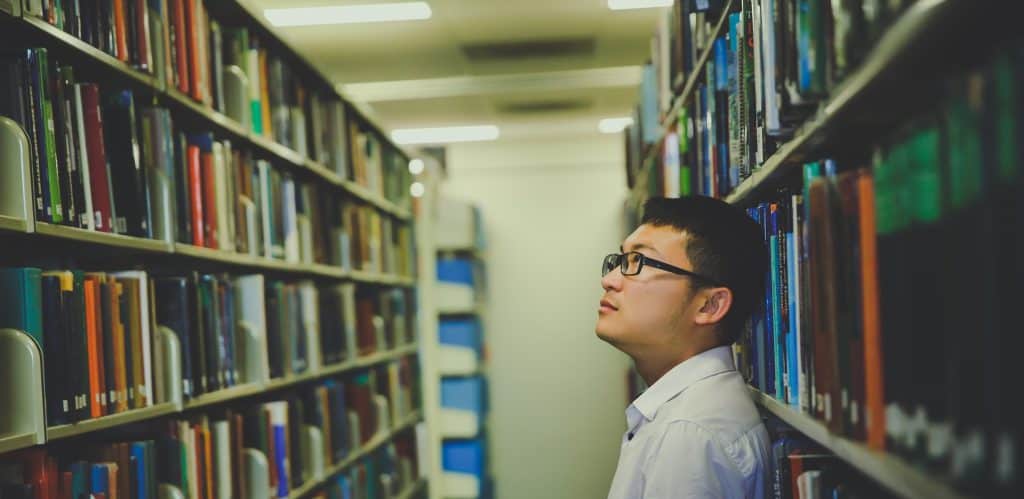 Man standing in between library shelves